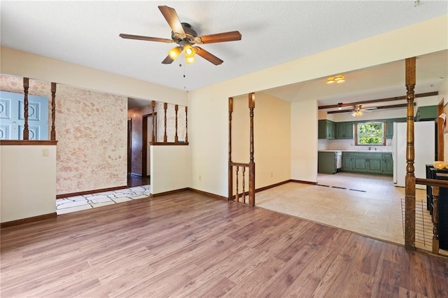 515 London Way, Belton, MO 64012 - unfurnished living room with ceiling fan, wood finished floors, baseboards, and a sink
