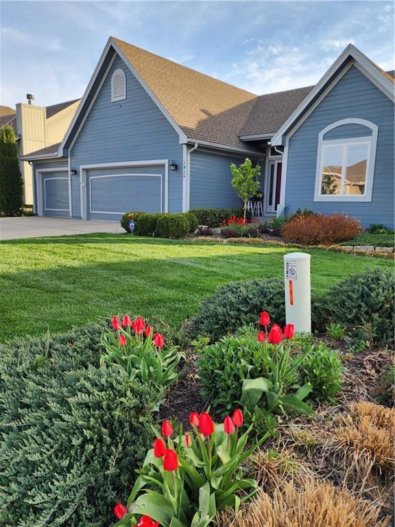 ranch-style home featuring concrete driveway, an attached garage, a shingled roof, and a front yard