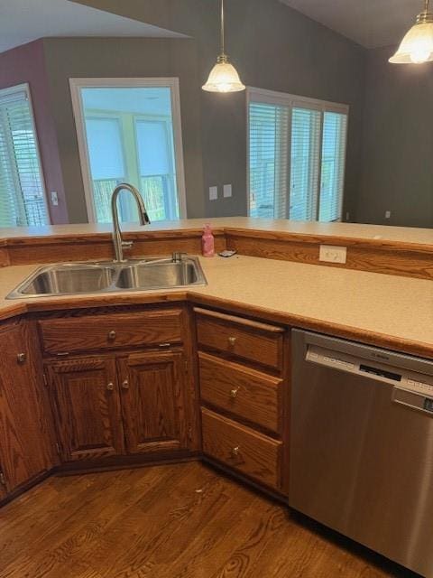 kitchen featuring pendant lighting, dishwasher, a sink, wood finished floors, and light countertops