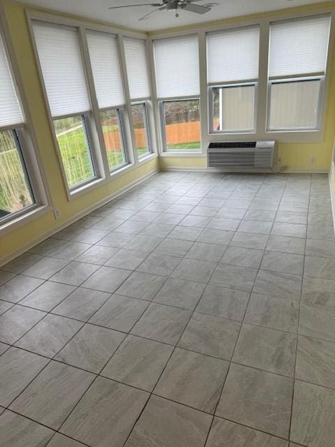 unfurnished sunroom featuring plenty of natural light, baseboards, and a wall unit AC