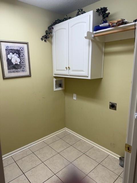 laundry area with hookup for an electric dryer, cabinet space, baseboards, and light tile patterned floors