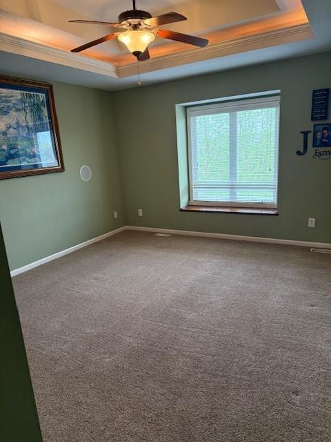 spare room with baseboards, a raised ceiling, ceiling fan, and carpet floors
