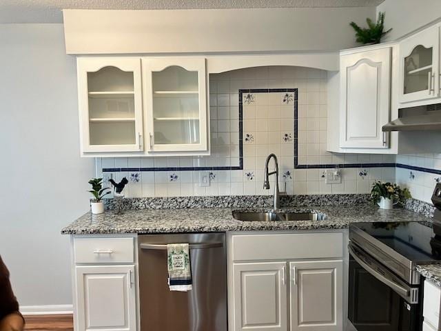 kitchen with under cabinet range hood, a sink, white cabinetry, backsplash, and appliances with stainless steel finishes