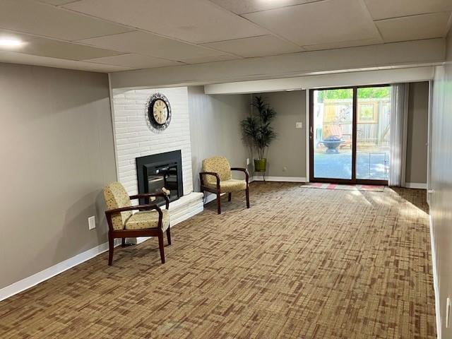 sitting room featuring a drop ceiling, a fireplace, and baseboards