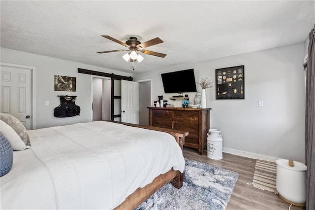 17201 NE 136th St, Kearney, MO 64060 - bedroom with a barn door, wood finished floors, ceiling fan, and a textured ceiling