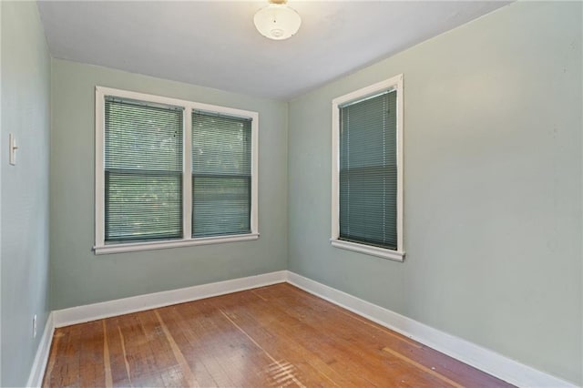 spare room featuring hardwood / wood-style floors and baseboards