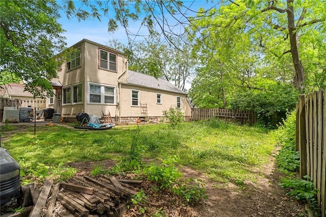 back of house with a fenced backyard and stucco siding