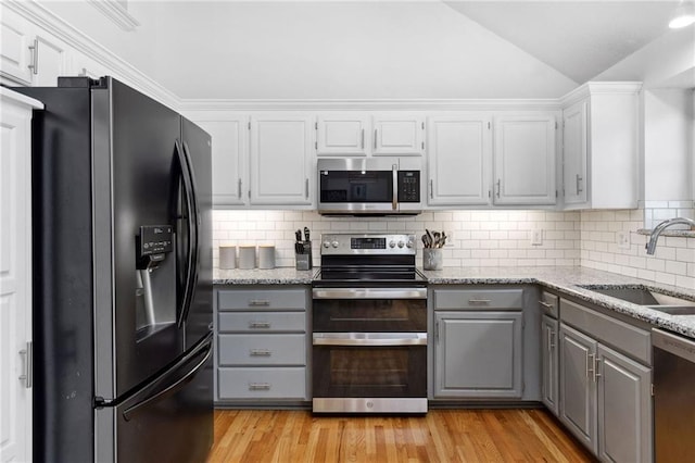 11004 N Kentucky Pl, Kansas City, MO 64157 - kitchen with stainless steel appliances, gray cabinetry, a sink, vaulted ceiling, and light wood finished floors