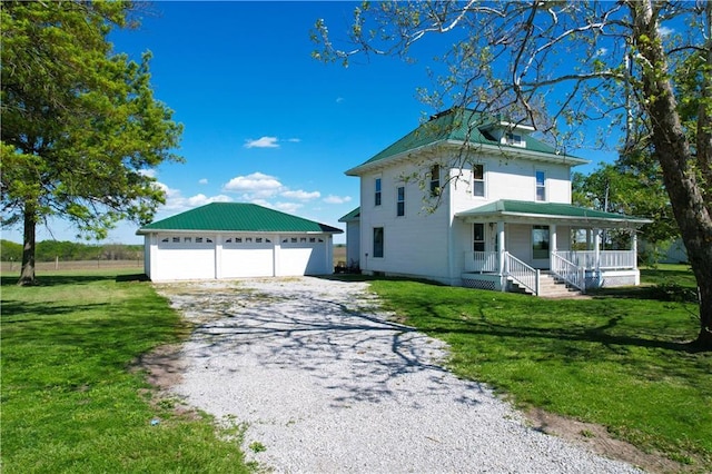 view of front of house featuring covered porch, a garage, a front lawn, and an outbuilding
