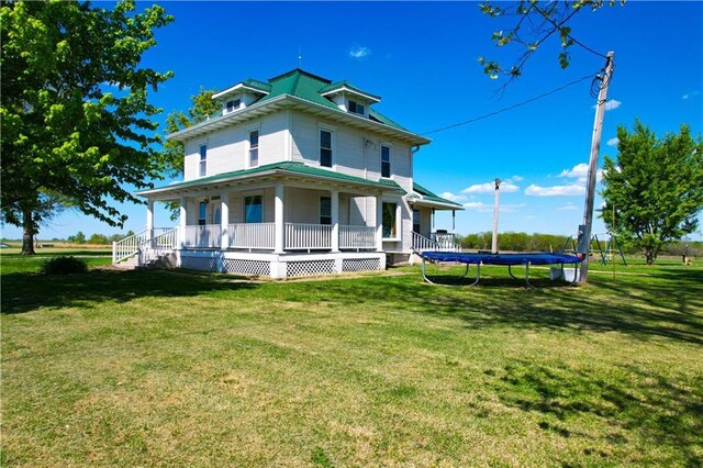 rear view of property with a trampoline, a porch, and a lawn