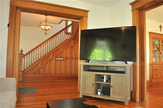 living area featuring stairs, a notable chandelier, and wood finished floors