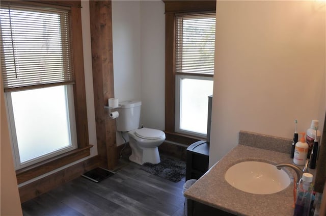 bathroom with toilet, a healthy amount of sunlight, visible vents, and wood finished floors