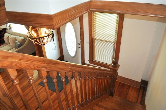 stairs featuring baseboards, a notable chandelier, and wood finished floors
