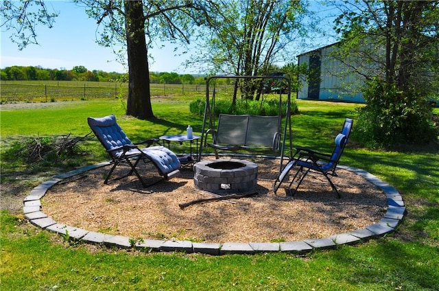view of yard featuring a fire pit, a rural view, and fence