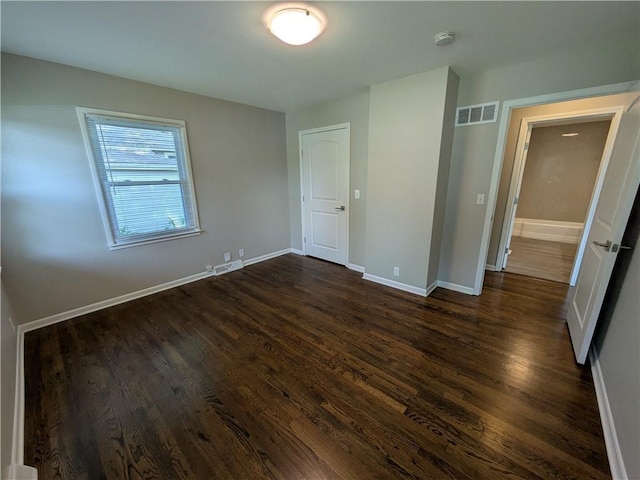 unfurnished bedroom with dark wood-style flooring and baseboards