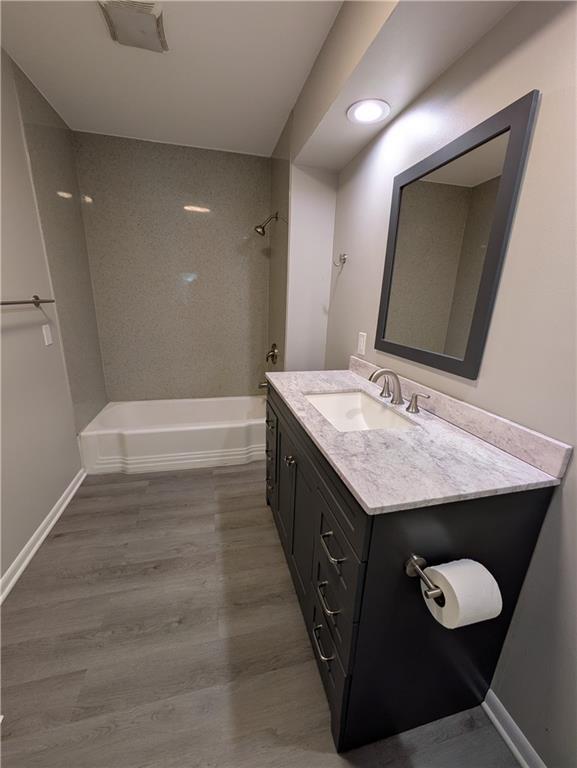 bathroom featuring tub / shower combination, vanity, and wood finished floors