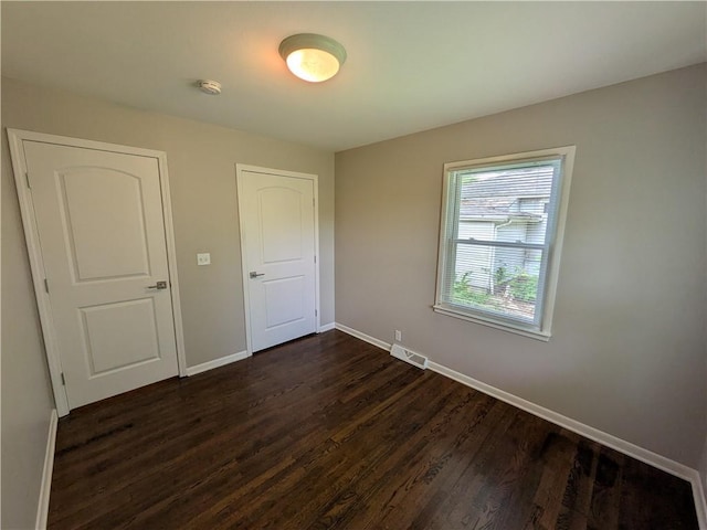 unfurnished bedroom with dark wood finished floors and baseboards