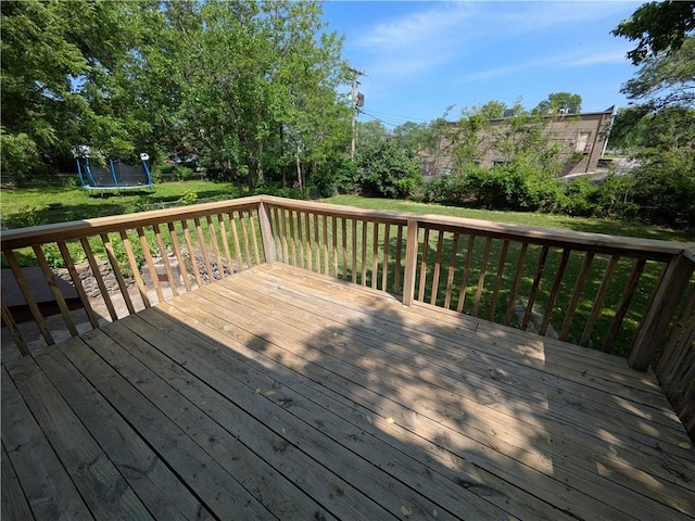 wooden terrace with a trampoline and a yard