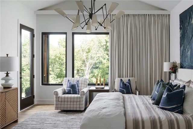 bedroom with a chandelier, wood finished floors, lofted ceiling, and baseboards