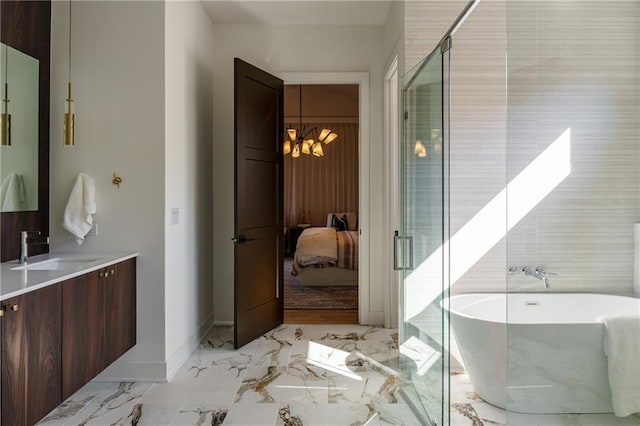 bathroom with a chandelier, marble tiled flooring, ensuite bathroom, a freestanding bath, and vanity