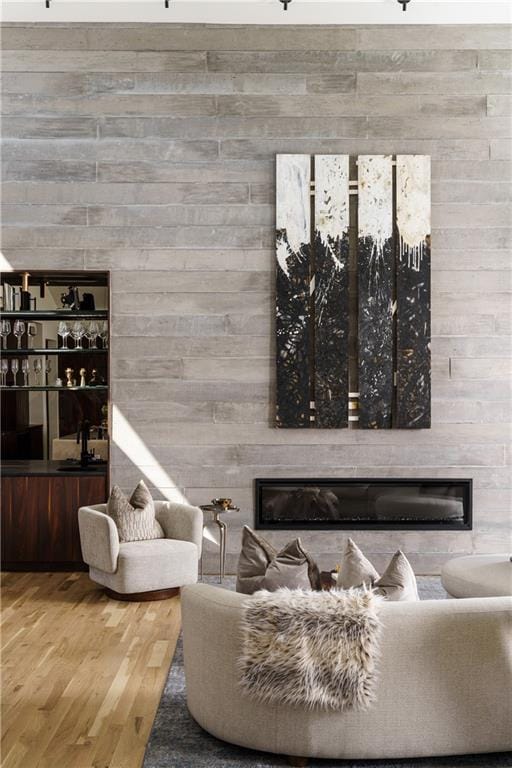 living room featuring a glass covered fireplace, wood finished floors, and wood walls