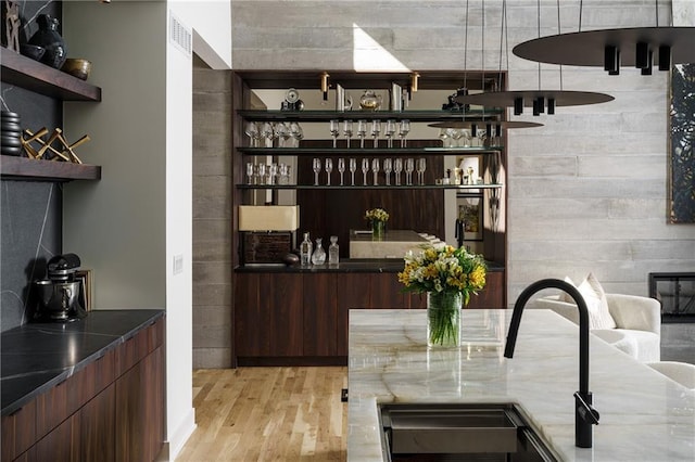 bar area featuring light wood-type flooring and a sink