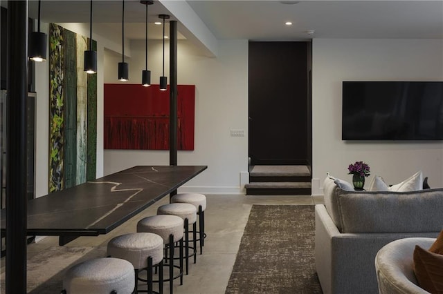 living area featuring finished concrete flooring, recessed lighting, and baseboards