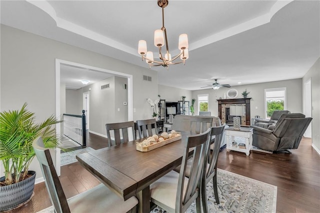 dining room with a chandelier, dark wood-style flooring, and a tray ceiling