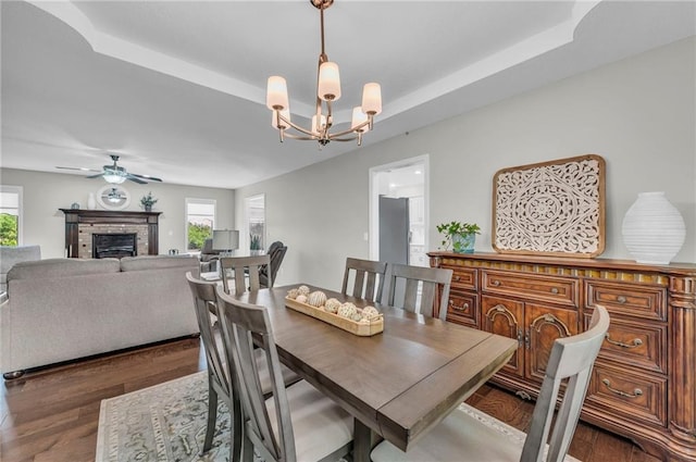 dining space with a chandelier, wood finished floors, a fireplace, and a ceiling fan