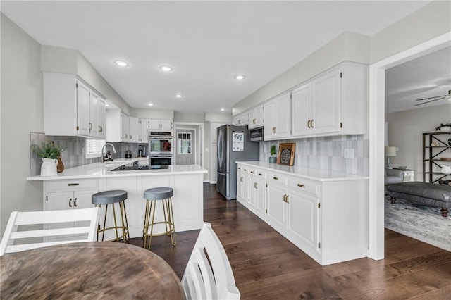 kitchen featuring a sink, stainless steel appliances, dark wood finished floors, decorative backsplash, and recessed lighting