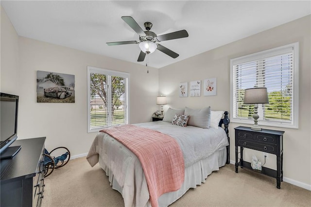 bedroom featuring light colored carpet, baseboards, and ceiling fan