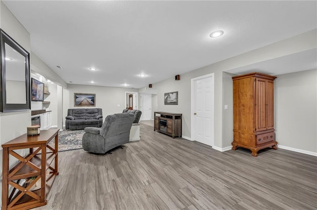 living room with light wood-style floors, baseboards, a fireplace, and recessed lighting