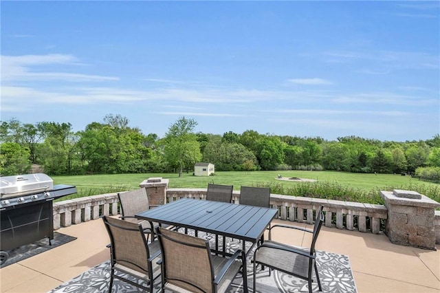 view of patio / terrace with a storage shed, outdoor dining area, an outbuilding, and a grill