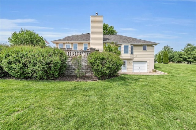 rear view of property featuring a chimney, a garage, and a lawn