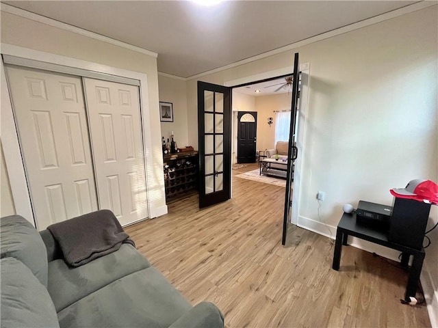 living area with light wood finished floors, french doors, baseboards, and ornamental molding
