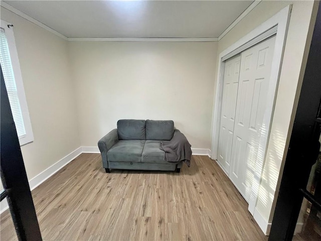 sitting room featuring baseboards, ornamental molding, and light wood-type flooring
