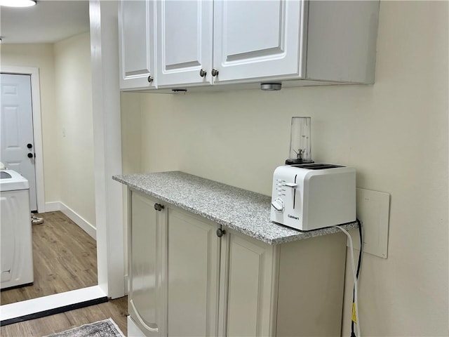 clothes washing area with laundry area, baseboards, light wood-type flooring, and a toaster