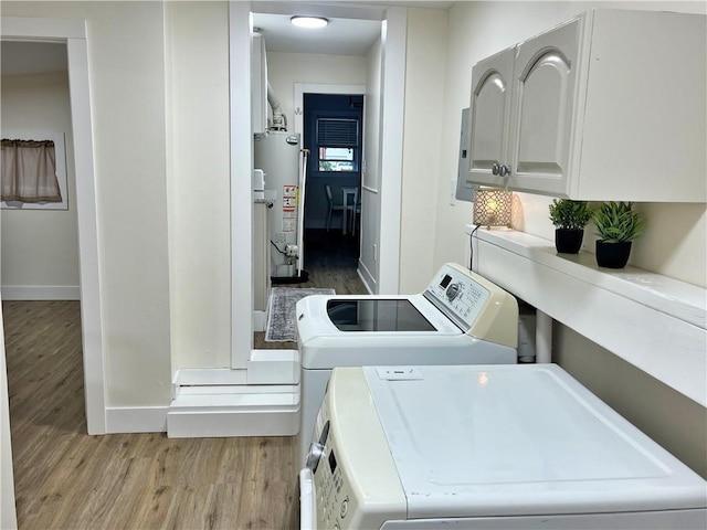 laundry area with light wood finished floors, baseboards, washer and dryer, and water heater