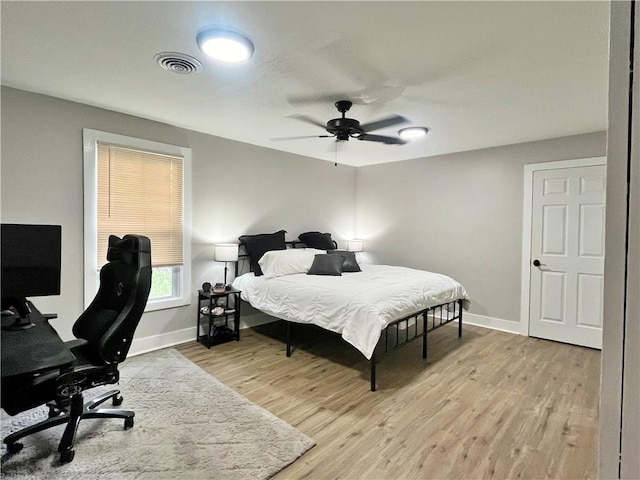 bedroom with ceiling fan, baseboards, visible vents, and light wood-style floors