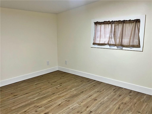 spare room featuring baseboards and wood finished floors