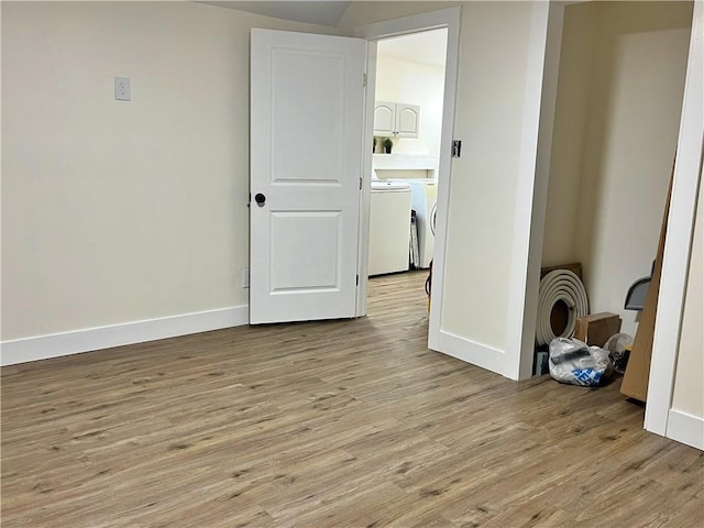 unfurnished room featuring baseboards, light wood-type flooring, and washer and clothes dryer