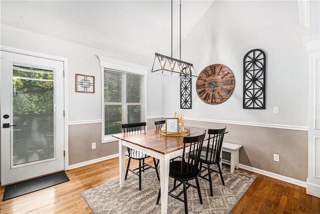 dining area featuring lofted ceiling, baseboards, and wood finished floors