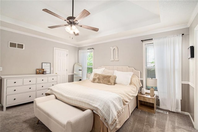 bedroom featuring a tray ceiling, crown molding, visible vents, and carpet floors