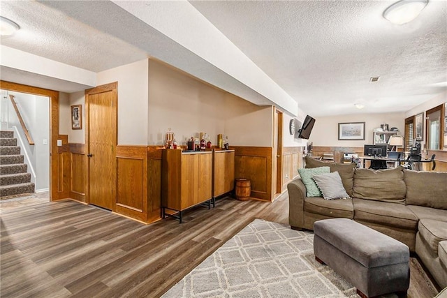 living room featuring wainscoting, a textured ceiling, stairway, and wood finished floors