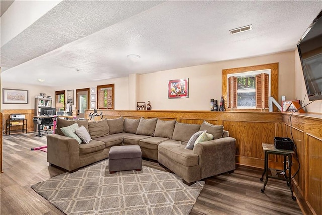 living area with visible vents, a textured ceiling, and wood finished floors