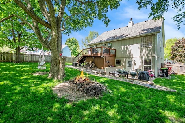 rear view of house with a yard, stairs, a wooden deck, a fire pit, and a fenced backyard