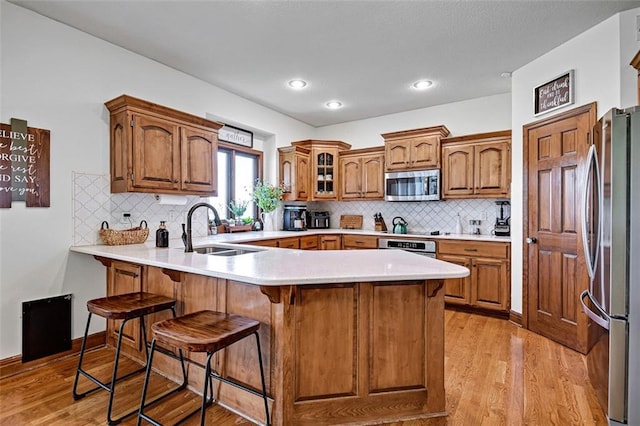 8904 NE 94th Pl, Kansas City, MO 64157 - kitchen with stainless steel appliances, a sink, a peninsula, a breakfast bar area, and light wood-style floors