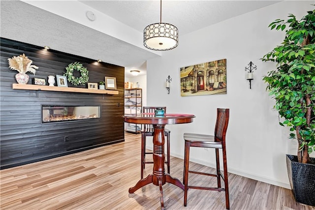 8904 NE 94th Pl, Kansas City, MO 64157 - dining room featuring wood finished floors, a glass covered fireplace, a textured ceiling, and baseboards