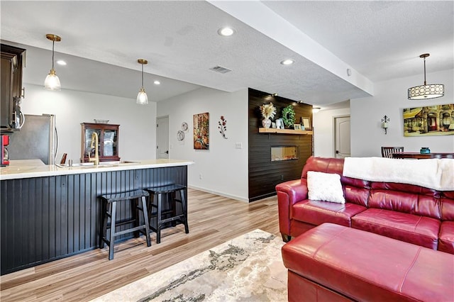 8904 NE 94th Pl, Kansas City, MO 64157 - living room featuring light wood-style floors, recessed lighting, a textured ceiling, baseboards, and bar