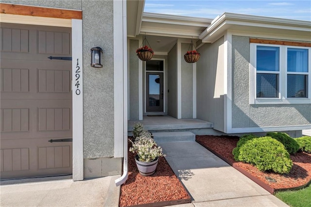 doorway to property with stucco siding and an attached garage